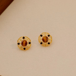 Macro detail of gold filigree earrings featuring polished tiger eye and onyx accents