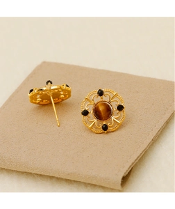 Detail of baroque gold earrings featuring brown tiger eye stone and black bead accents