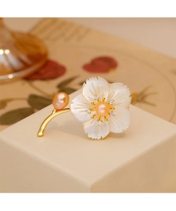 Vue détaillée d'une broche fleur élégante en nacre blanche avec perle rose sur monture dorée