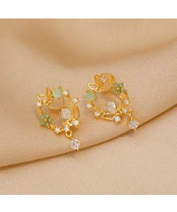 Macro detail of vintage gold butterfly floral earrings with green gems on champagne silk