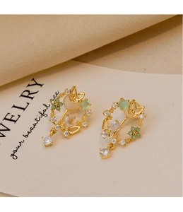 Detail of gold floral butterfly clip earrings with zircon and light green beads