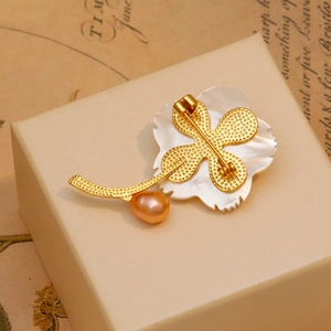 Broche fleur en nacre élégante avec plaquage or et perle sur une boîte à bijoux