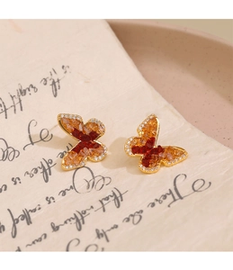 Détail de boucles d'oreilles papillon avec cristaux ambrés et bordures en zircon brillant