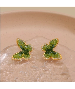 Vue macro des boucles d'oreilles papillon en cristal vert avec diamants fins et dorure