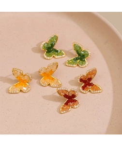 Détail de boucles d'oreilles papillon avec cristaux dégradés et plaqué or