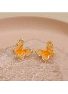 Vue macro des boucles d'oreilles papillon en résine orange et petits cristaux blancs