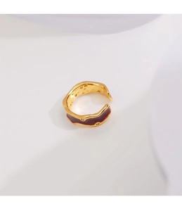 Détail d'une bague ouverte dorée avec émail bordeaux et zircons cubiques scintillants