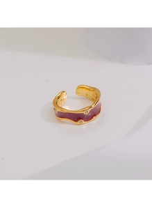 Détail d'une bague dorée ondulée avec émail rouge vin et accents de zircone