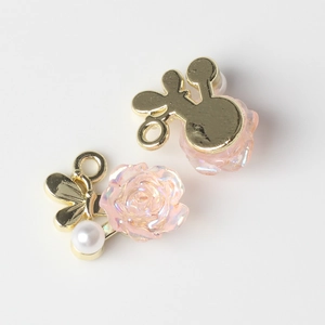 Vue détaillée des pendentifs fleur en résine et perle avec base papillon dorée