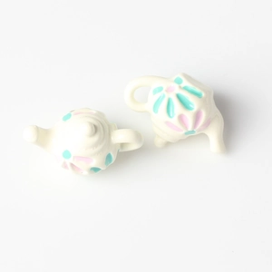 Macro view of miniature alloy teapot charms with floral patterns for DIY jewelry making