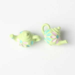 Close-up of mini light green floral teapot pendants for DIY jewelry making and crafts