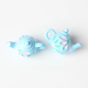 Close-up of light blue miniature teapots with floral patterns for DIY jewelry making
