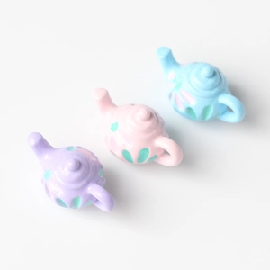 Detailed view of mini macaron colorful teapot charms in pink, purple, and blue resin