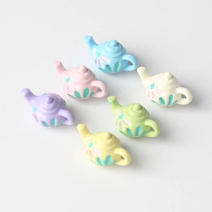 Detail of mini resin teapots in macaron colors with embossed floral patterns for DIY crafts