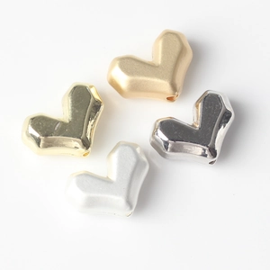 Vue macro de perles en forme de cœur pour bijoux DIY en finitions dorées et argentées