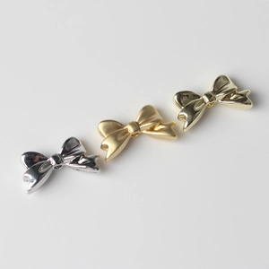 Dettaglio di perline in lega a forma di fiocco in argento e oro per gioielli DIY