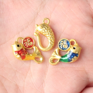 Hand holding koi fish pendants with Fu character tags in brass enamel finish