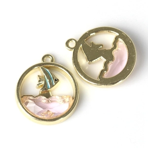 Detail van ronde walvishanger met blauwe vis en roze kristal in gouden afwerking