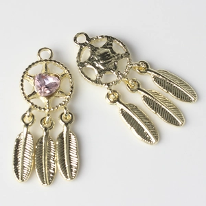 Macro detail of golden dreamcatcher pendant with pink heart gemstone and metal feathers