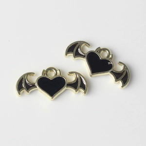 Detalle de colgantes de corazón con alas de diablo en esmalte negro y acabado dorado