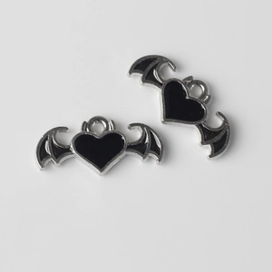 Detalle de dijes de alas de murciélago y corazón con esmalte negro para joyería artesanal