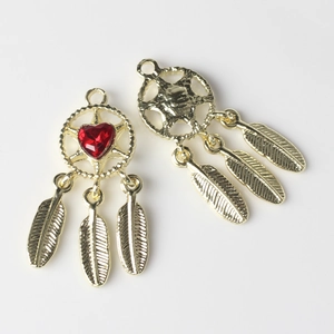 Macro view of golden dreamcatcher pendant featuring a red heart stone and feather charms