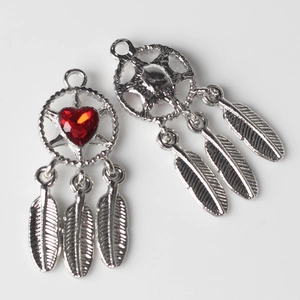 Macro detail of dreamcatcher pendant with red heart zircon and silver feathers