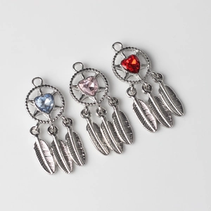 Detailed view of silver dreamcatcher pendants with heart gems and three metal feathers