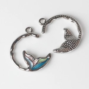 Detail view of silver whale tail pendants with colorful enamel and textured finish