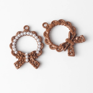 Detailed view of a brown alloy wreath pendant with white pearl accents and a bow knot