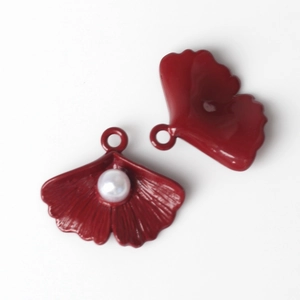 Detail of two red ginkgo leaf pendants with white pearl inlay and radial texture