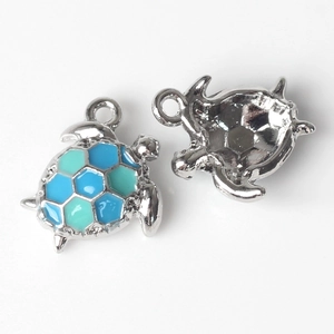 Detailweergave van schildpadbedels met blauw en muntgroen emaille op zilver metaal
