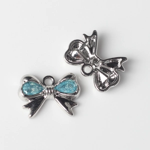 Detalle de colgante de lazo azul con base plateada y anillo para joyería artesanal
