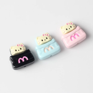 Macro detail of cat-in-bag charms for DIY jewelry making with M-logo and colorful resin finish