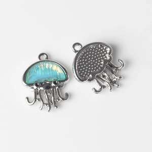 Vue macro de pendentifs méduse en alliage argenté avec incrustation résine et dos gravé