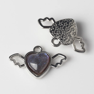 Macro detail of alloy heart pendant with purple glitter resin and angel wings design