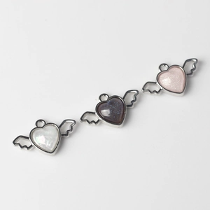 Detailed view of heart-wing resin pendants in white, blue, and pink for DIY jewelry