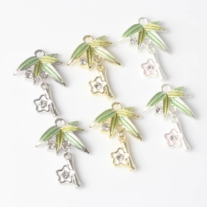 Detailed view of alloy bamboo leaf and flower charms with green enamel and zircons