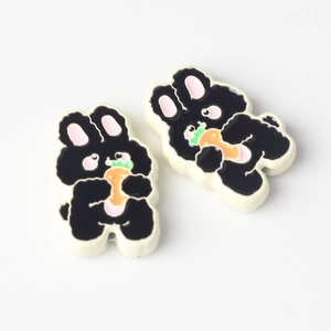 Detailed view of two cute black rabbit charms with orange carrots for DIY jewelry