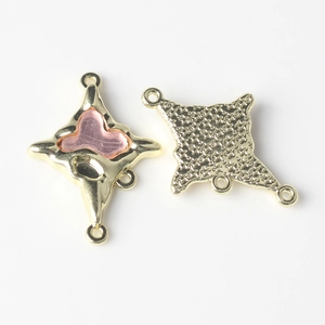 Detail of gold alloy four-way cross connector with pink heart resin inlay and textured back