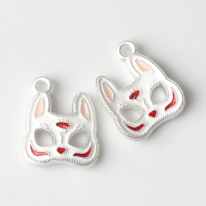 Macro detail of alloy fox mask charms with white enamel and red painted accents for DIY