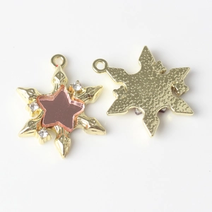 Detail of star-shaped alloy pendants with pink resin inlay and textured gold-plated back