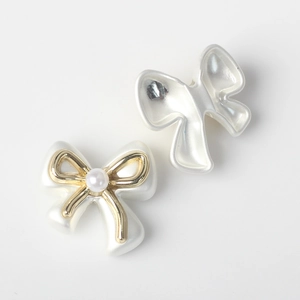 Macro detail of pearlescent bow beads with golden metal frame and pearl centerpiece