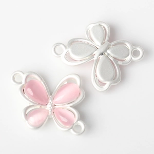 Macro detail of alloy butterfly connectors with pink resin inlay for DIY jewelry making