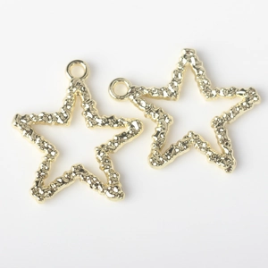 Macro detail of two gold-plated star pendants with hand-hammered lava texture and top rings