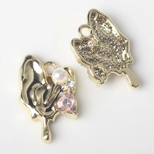 Macro detail of golden butterfly charms with pearls and pink heart-shaped crystals