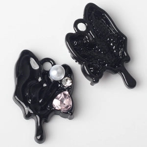 Detailed view of black enamel butterfly charms with pink heart crystal and pearls