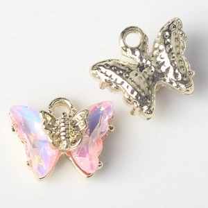Detailed view of alloy butterfly charms with iridescent purple zircon and gold metal backing