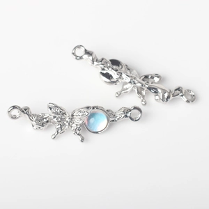 Detalle de conector mariposa plateado con pavé de circones y gema azul claro