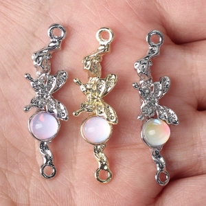 Colgante de mariposa con piedra de ópalo en acabados oro y plata sostenido a mano